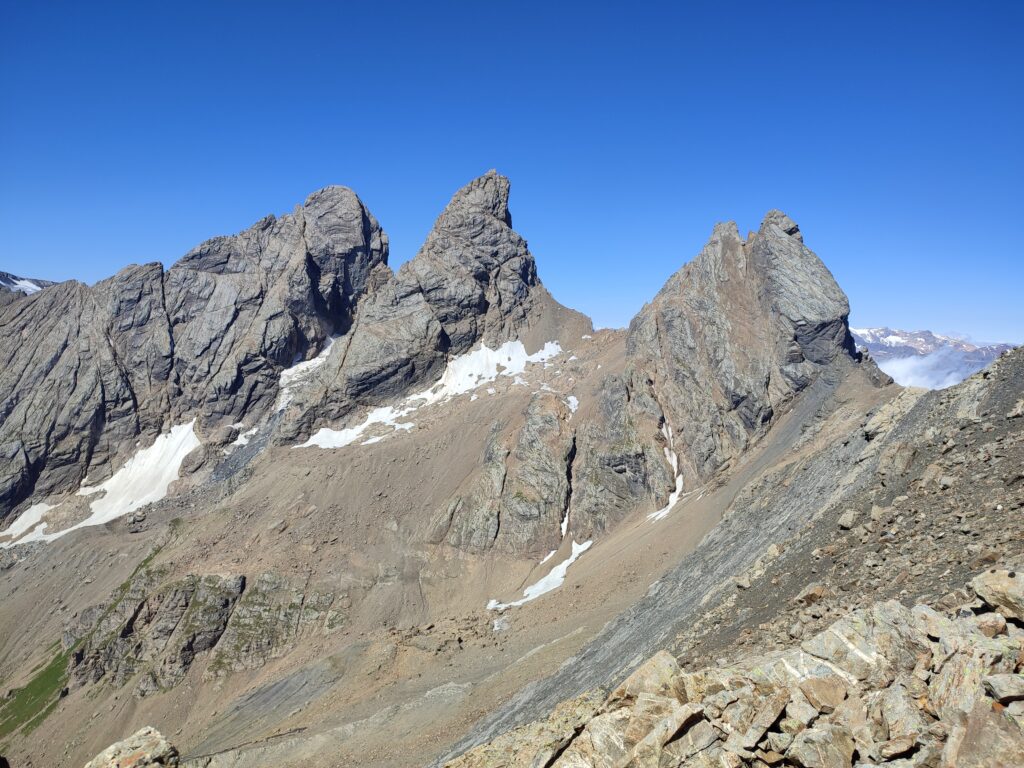 3 sommets de montagnes sur fond de ciel bleu. Au pied des sommets, des pierres, rien que des pierres, des champs de pierres.